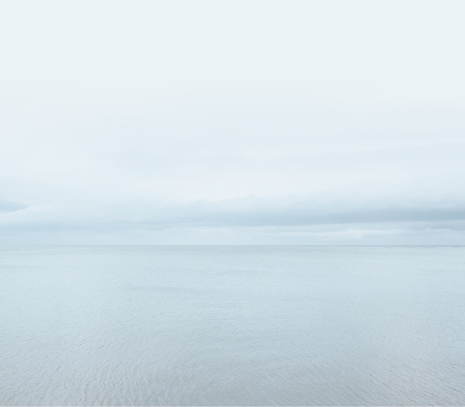 Minimalistic view of the ocean under an overcast sky.