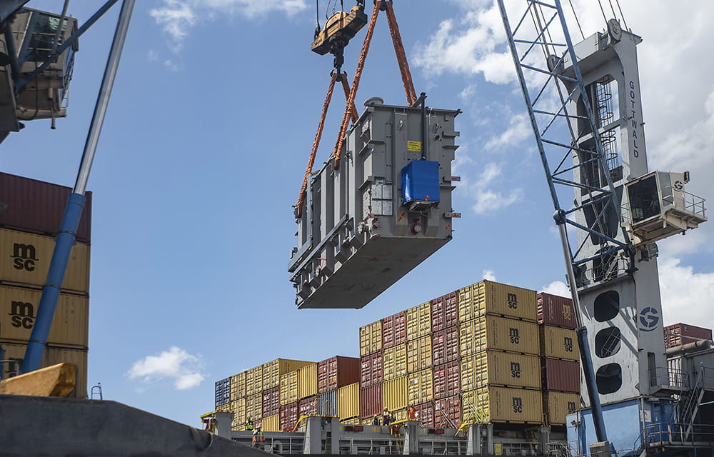 A crane elevates a transformer from a vessel
